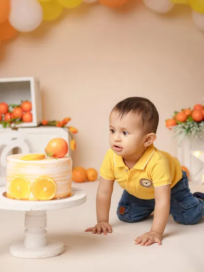 The adventure begins! A little boy crawls towards his orange-themed birthday cake, ready for some messy fun.