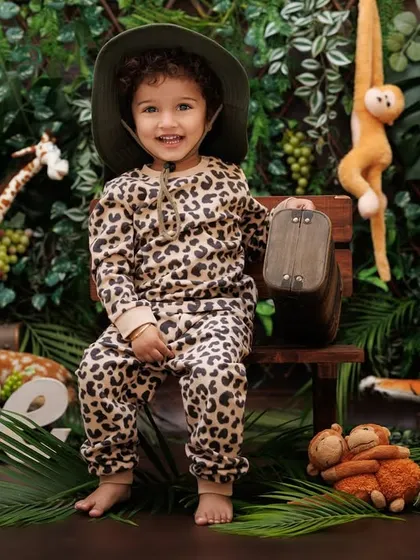 Welcome to the jungle! A happy little explorer in a leopard print outfit is ready for his first birthday adventure.