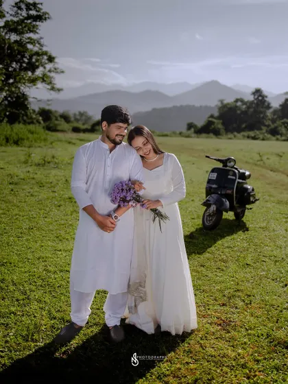 A sweet and romantic pose, with her resting her head on his shoulder. The scooter in the background adds context to their story.