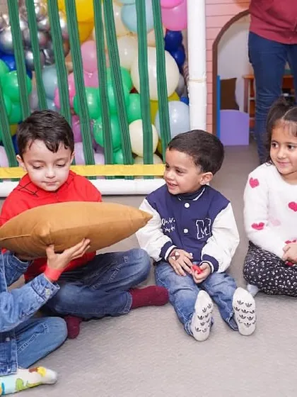 Children sitting in a circle, playing a game of pass the parcel, guided by our staff.