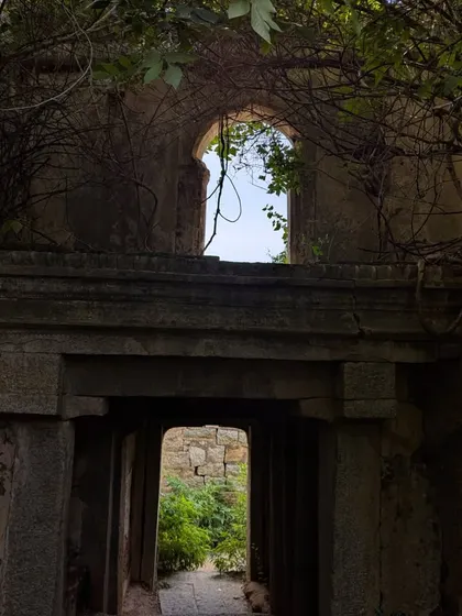 The beauty of Gudibande fort, where nature has reclaimed parts of the ancient stone structure. The interplay of architecture and overgrown vines creates a poetic scene.
