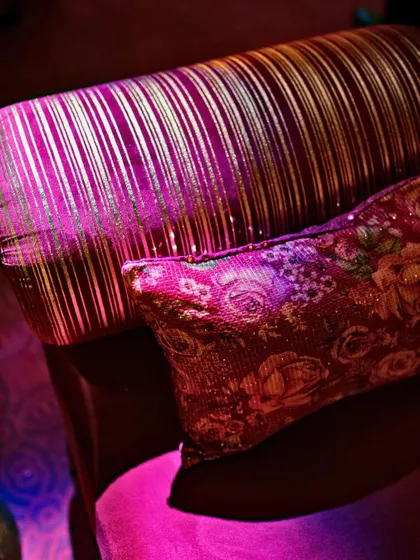 A detail shot of the rich, textured fabrics used in the Sangeet decor, including a striped gold and magenta cushion.