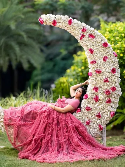 Lying gracefully on the floral moon prop, the mom-to-be looks like a sleeping beauty in this dreamy and artistic garden portrait.