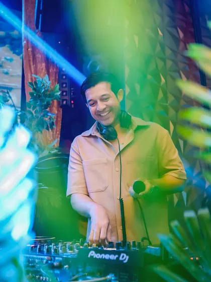 A candid shot of me smiling while mixing, framed by the club's greenery.