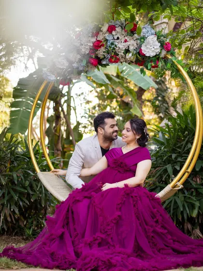 A romantic moment on the floral swing, with the rich purple gown adding a touch of royalty to the lush garden scene.