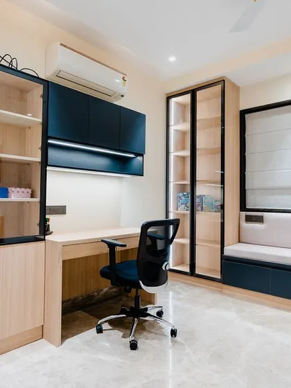 A productive and inspiring study room. The design includes two separate workstations, plenty of open and closed storage with glass-front cabinets, and a comfortable seating nook by the window.