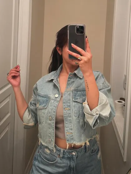 A classic denim-on-denim look, featuring a cropped jacket and jeans in a mirror selfie.