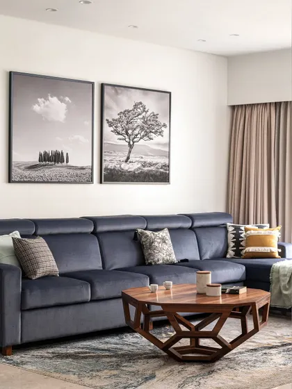 This living room is a cozy cocoon, designed for ultimate relaxation. The deep, inviting sofa is perfect for sinking into, while the geometric wooden coffee table adds a touch of modern character. The black and white art provides a classic, sophisticated backdrop.