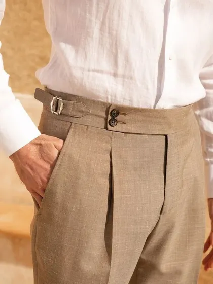 A close-up of our tailored trousers, featuring a Gurkha-style waistband with double buttons and side adjusters. This detail offers a unique look and a secure, comfortable fit.