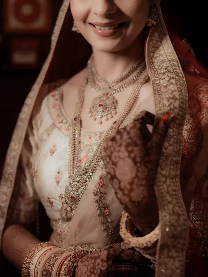 A detail shot focusing on the bride's magnificent layered necklace and the delicate embroidery of her lehenga.