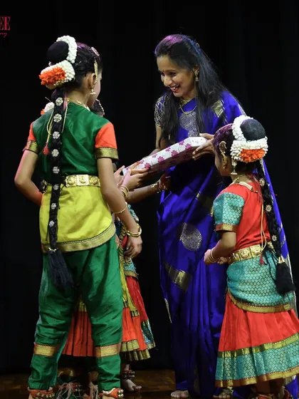 A teacher sharing a proud moment with her young students after their performance at Nritya Sanje. We are a family that celebrates each other's successes.