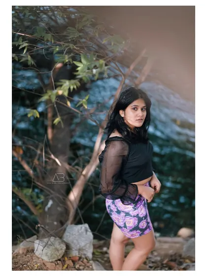 A vertical composition from the same outdoor shoot, focusing on her pose and the natural textures of the location.