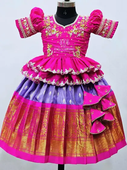 A grand tiered lehenga made from tissue Kanchi Pattu in shades of pink and purple. The blouse is heavily embroidered.