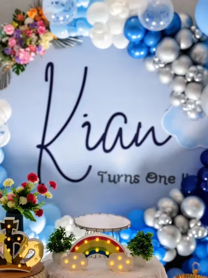 A close-up of the personalized backdrop for Kian's first birthday, framed by a gorgeous balloon arch with pops of fresh flowers.