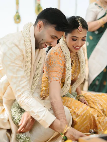 A candid moment during a South Indian wedding ceremony. The couple's shared smile shows their happiness and comfort with each other.