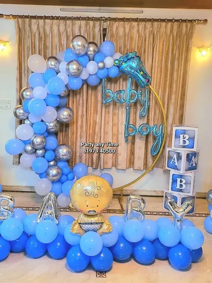 A "Welcome Baby Boy" decoration with a blue, white, and silver balloon arch, "BABY" blocks, and character foil balloons.