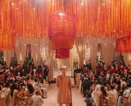 A moment of joy as the groom enters the wedding venue, with guests looking on from under the massive floral chandelier.
