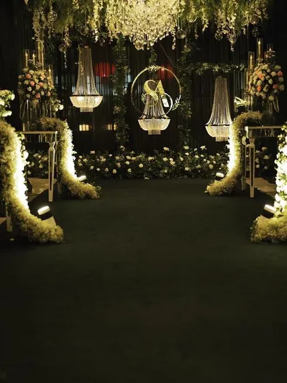 The view down the aisle towards the floral and chandelier backdrop, showing how the design creates a sense of depth and enchantment for the entrance.
