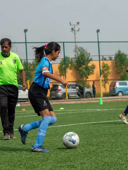 A young female player dribbles the ball with precision during a training session, showcasing her focus and skill.
