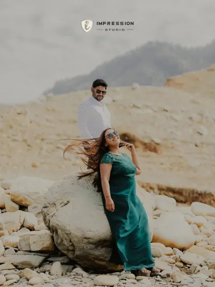 A stylish pose against a rocky, lakeside terrain. The wind in her hair and their cool demeanor give this shot a relaxed yet fashionable vibe, perfect for a modern pre-wedding album.