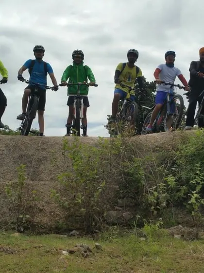 Riders silhouetted against the sky as they stand on a rock ledge with their bikes.