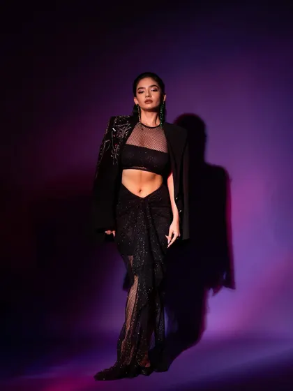 This shot from the GQ series focuses on the complete look, highlighting the silhouette of the outfit against the purple and red lighting.