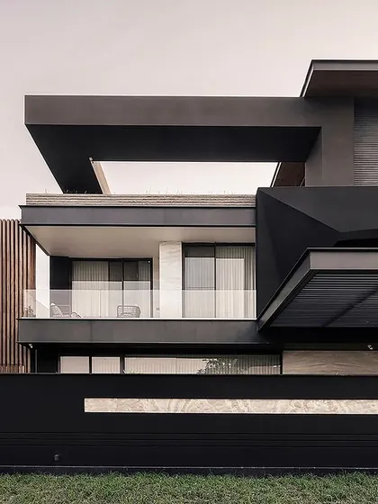 A closer view of the Carbonado residence, highlighting the interplay of textures and geometric forms. The design balances robust, dark masses with transparent glass and warm wooden accents for a sophisticated, modern facade.