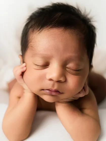 The classic "chin on hands" pose against a clean white background. This pose is perfect for showcasing the baby's sweet face and peaceful slumber.