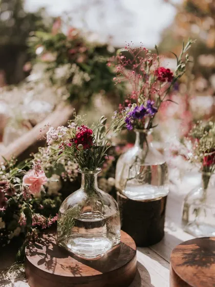 A close-up of the wildflower arrangements in glass bottles, perfect for a rustic, bohemian-themed event.