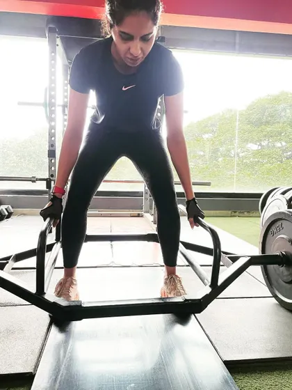 A client performs a trap bar deadlift, demonstrating her strength and focus.