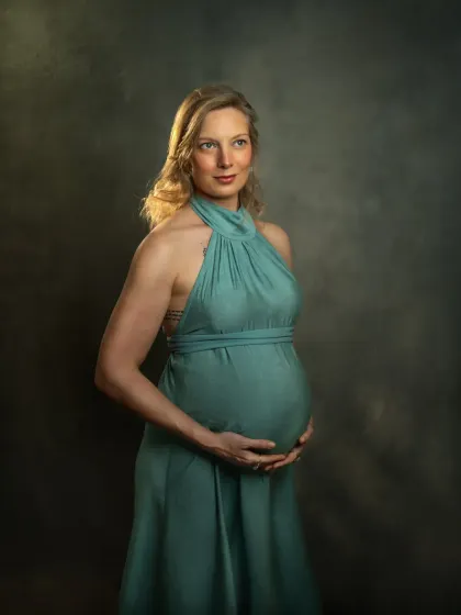 A duplicate of ID 81, this classic maternity portrait features an expecting mother in a beautiful sea-green gown. The studio lighting highlights her form and the texture of the fabric, creating a timeless, painterly effect.