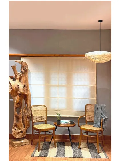 This cozy seating arrangement, featuring my teak and rattan chairs, is illuminated by a flattened globe pendant. The light fixture adds a layer of softness and texture to the clean lines of the room.