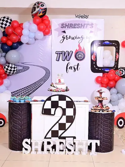 Shresht is "two fast" with this exciting race car theme for his second birthday. We used a checkered flag design, a custom backdrop with a winding road, and car-themed props to create a high-speed celebration.
