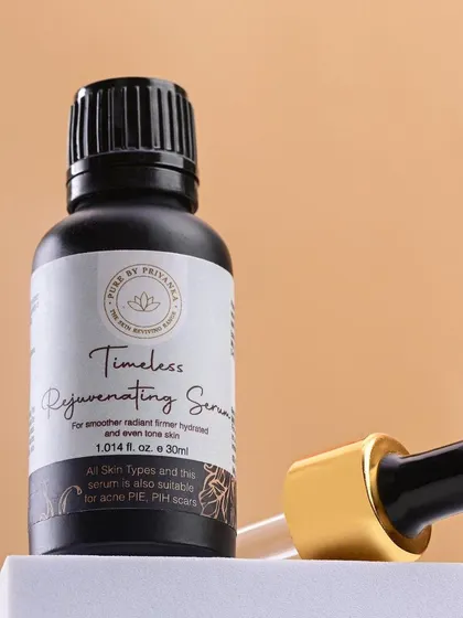 A close-up of Pure by Priyanka's "Timeless Rejuvenating Serum." The dark bottle and gold-accented dropper convey a sense of luxury and potency.