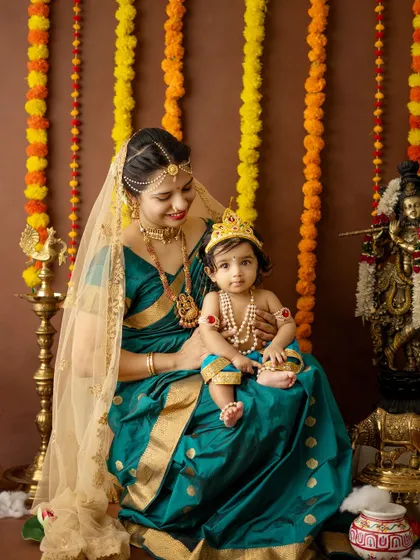 A serene portrait of a mother and her baby girl in their festive Janmashtami costumes.