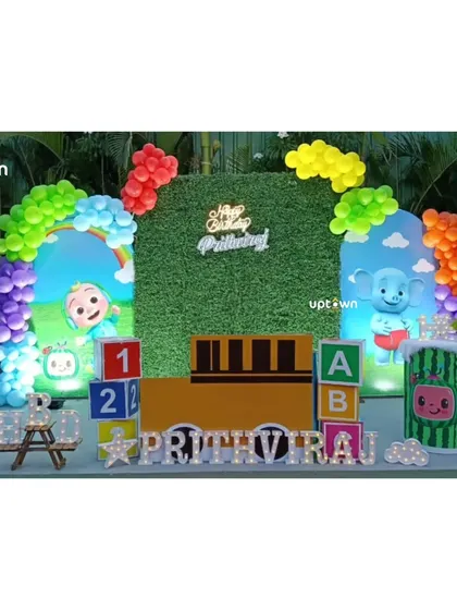 A full view of the Cocomelon party stage, showing the arrangement of the character cutout's and the vibrant balloon arches.