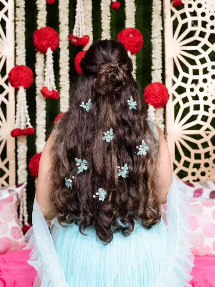 Fun and candid moments from a mehendi ceremony. The bride's makeup is fresh and playful, with a winged liner and glowing skin, perfect for celebrating with her loved ones. The hairstyle is a soft half-updo with pretty accessories.