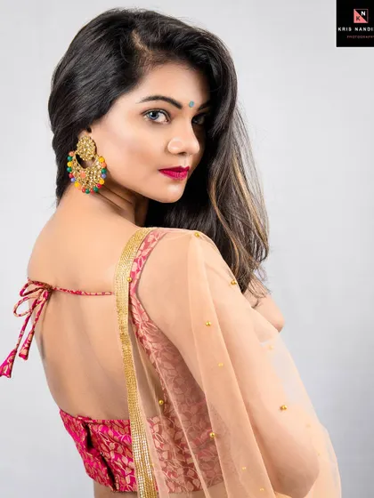 A classic back-pose portrait of a woman in a beautiful lehenga. The focus is on the intricate design of the blouse and the delicate fabric of the dupatta, showcasing the elegance of Indian attire.