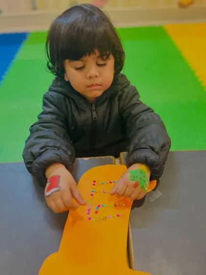 A boy decorates a large yellow stocking, a craft that allows for big movements and creative expression.