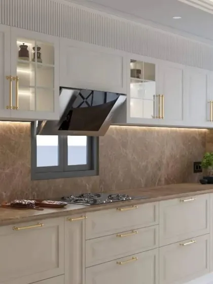 A luxurious kitchen design with off-white cabinets, gold handles, and a brown marble backsplash. The glass-front upper cabinets with internal lighting add a sophisticated touch for displaying fine crockery.