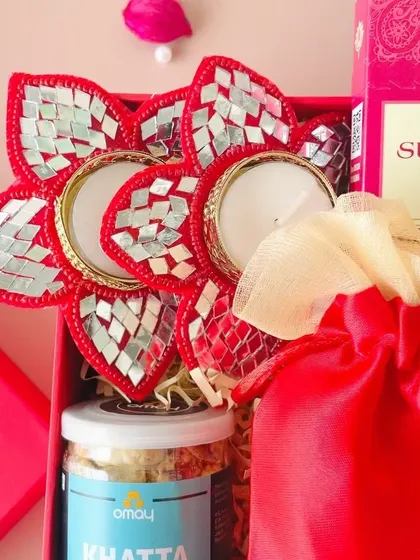 A detailed shot of our mirror-work flower-shaped diyas. These handcrafted items are a festive and vibrant addition to our Diwali hampers.