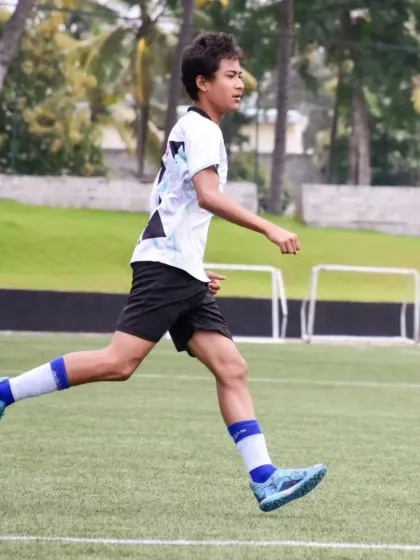 A young footballer runs with purpose, his form and determination reflecting the professional training environment at our school.