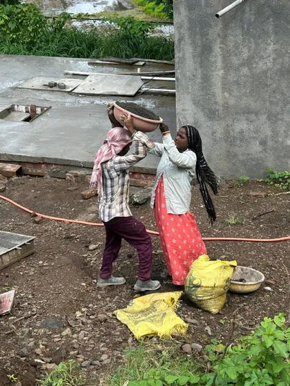 A candid moment of teamwork on the construction site in Alibaug. This image captures the physical labor and collaboration that are the backbone of any architectural project, turning raw materials into finished spaces.