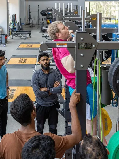 A UKSCA assessor demonstrates a pull-up, a key measure of upper body strength, to a group of trainees.