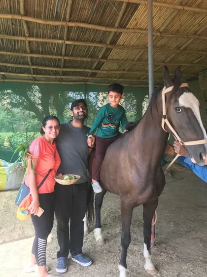 A family poses for a picture with their son enjoying a horse ride, guided by our trained staff.