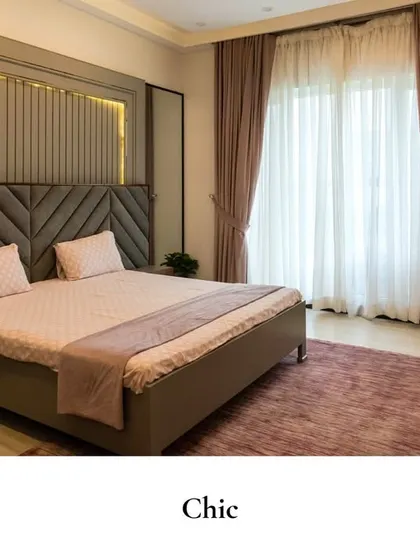 This chic bedroom features a textured, diagonally-patterned upholstered headboard and fluted wall panels with soft backlighting for a modern, sleek touch.
