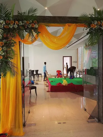 This floral entrance arch uses yellow drapes and bouquets of fresh flowers with green foliage. It's a bright and cheerful way to welcome guests to any celebration.