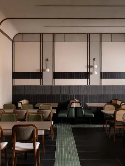 This wider view shows the general seating area with its clean lines and organized layout. The repetition of wooden chairs and tables creates a sense of rhythm and order in this part of the restaurant.