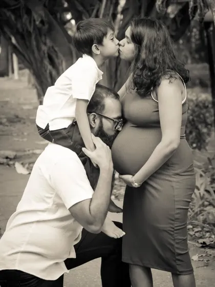 A truly touching black and white portrait. The father kisses the baby bump, while the older brother gives his mom a sweet kiss, capturing a moment of pure family love.