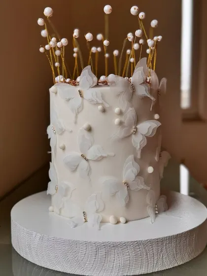 A dreamy all-white cake adorned with delicate wafer paper butterflies and elegant toppers.